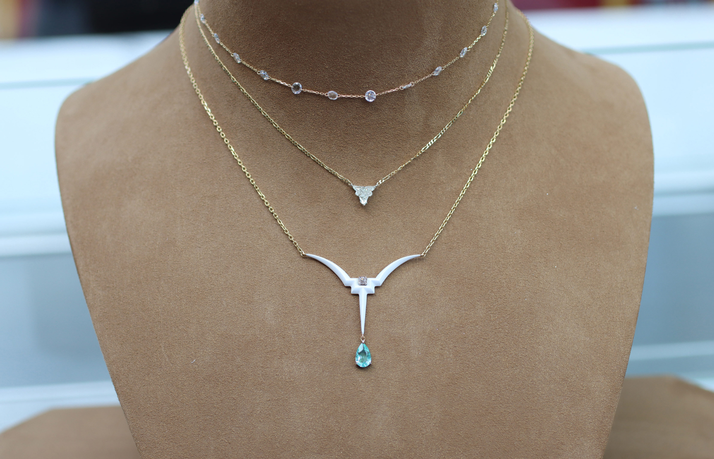 Inés Nieto necklace stack featuring the Taura necklace with a Paraiba tourmaline drop, a Taura necklace with a bull-shaped diamond, and a Rosary choker