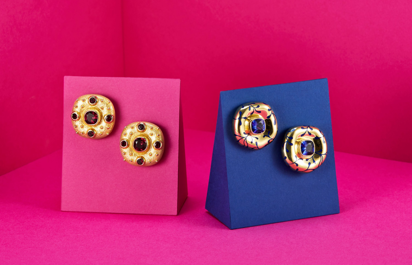 Elizabeth Gage Rhodolite Garnet Ottoman earrings in gold and garnet, alongside a pair of Tanzanite earrings in gold, enamel and tanzanite