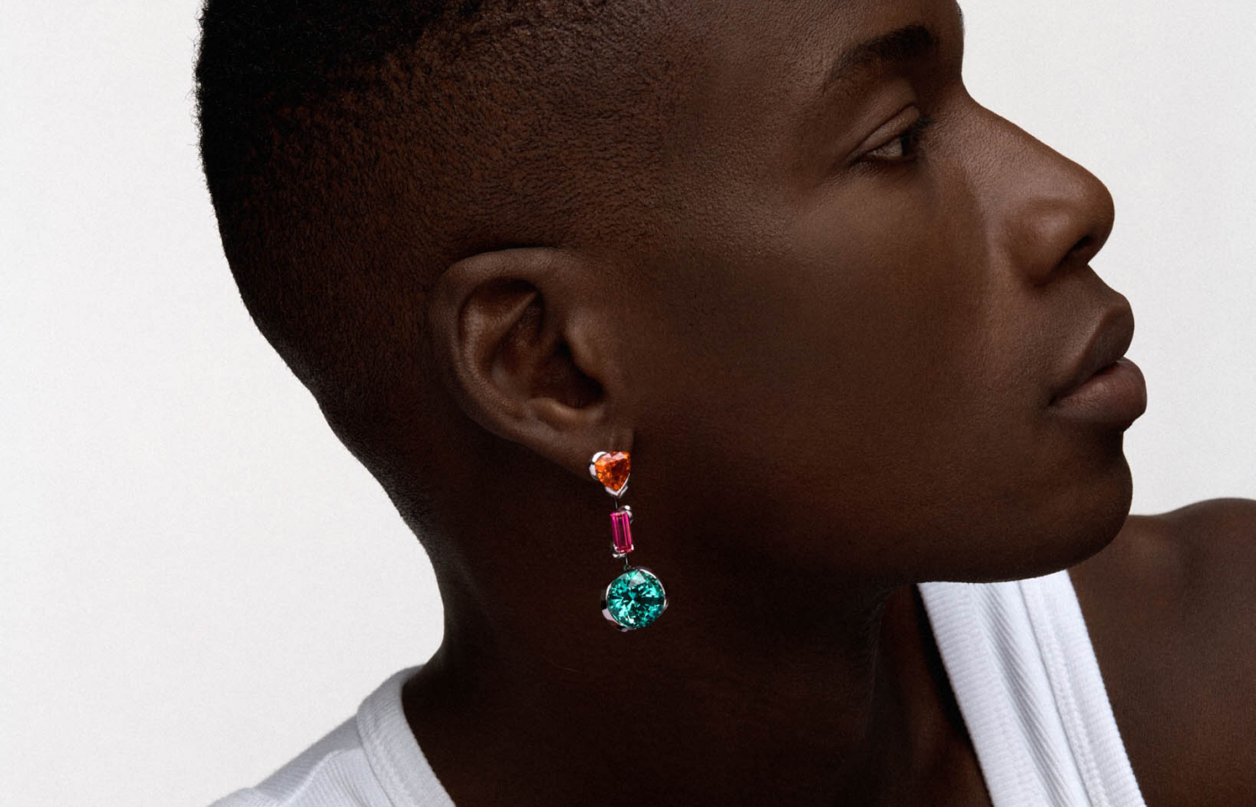  Model wearing REZA Triple Drop earrings in white gold, garnet, tourmaline and sapphire