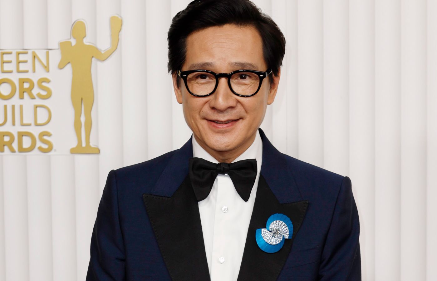 Actor Ke Huy Quan at the SAG Awards wearing the De Beers The Alchemist of Light Ascending Shadows brooch with a 2.70-carat oval-shaped fancy grey diamond