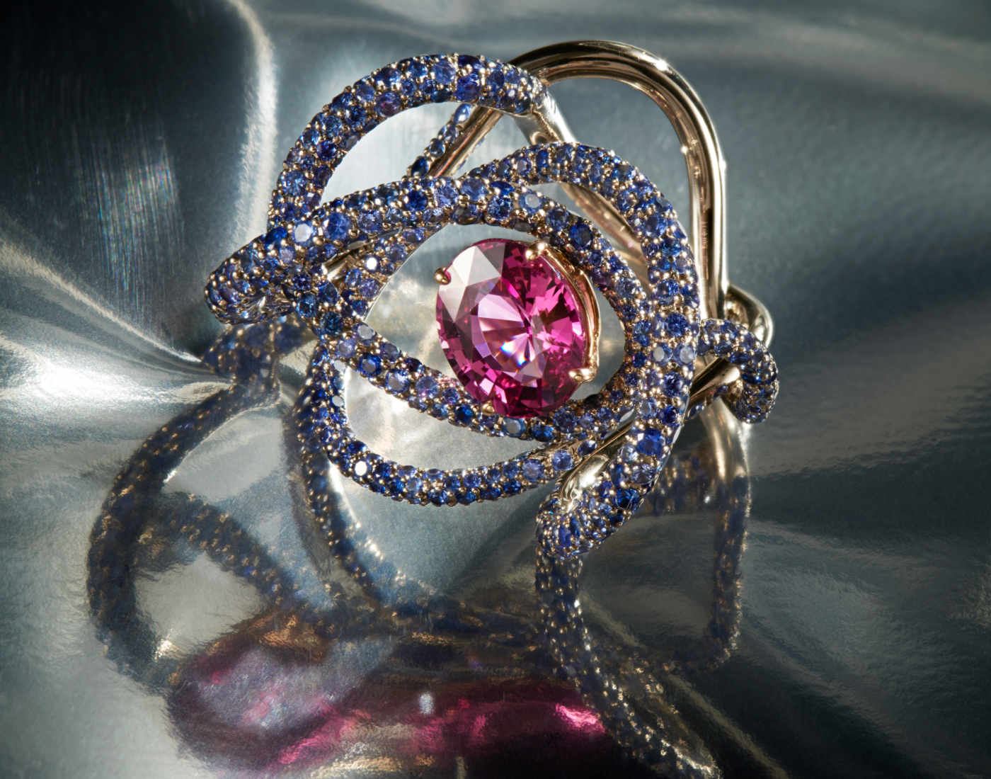  Neha Dani Kephi ring with a natural (no heat) oval, reddish pink sapphire of 4 carats, surrounded by a unique pattern of round blue sapphires