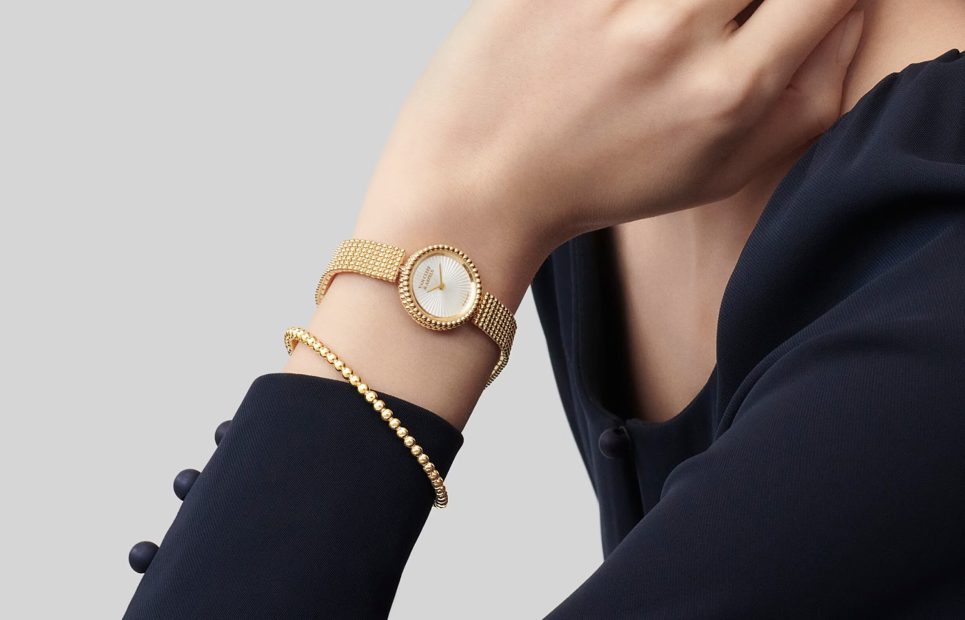 A model wears the Van Cleef & Arpels Perlée watch with a 23 mm case in 18k yellow gold, a mother of pearl dial, and a ‘Golden Bead’ bracelet strap 