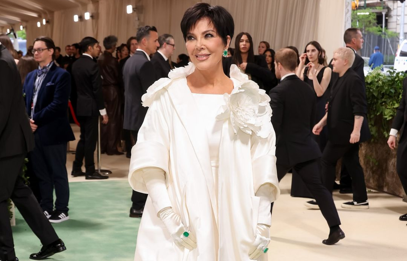 Kris Jenner attends the Met Gala 2024 in a floor length Oscar de la Renta gown and elbow-length white opera gloves, complete with large emerald-set cocktail rings 