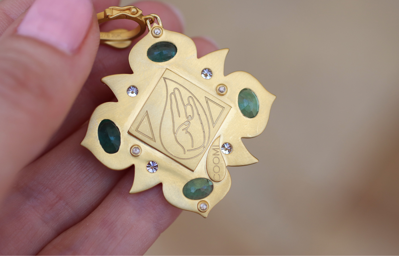  The reverse side of a COOMI Trinetra pendant engraved with the Buddhi mudra yoga hand technique, crafted in 20k yellow gold 
