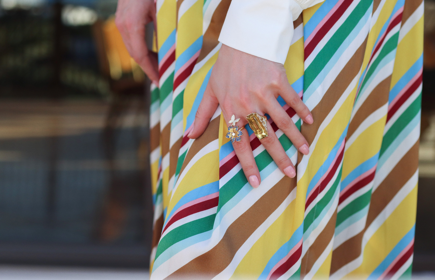 Katerina Perez wears rings by Lisa Nik, including the Butterfly Flower Bypass ring from the Rainbow collection with 1.6 carats of yellow and blue sapphires and diamonds, alongside a 20.30 carat golden beryl and diamond ring from the Colors collection, both in 18k yellow gold 