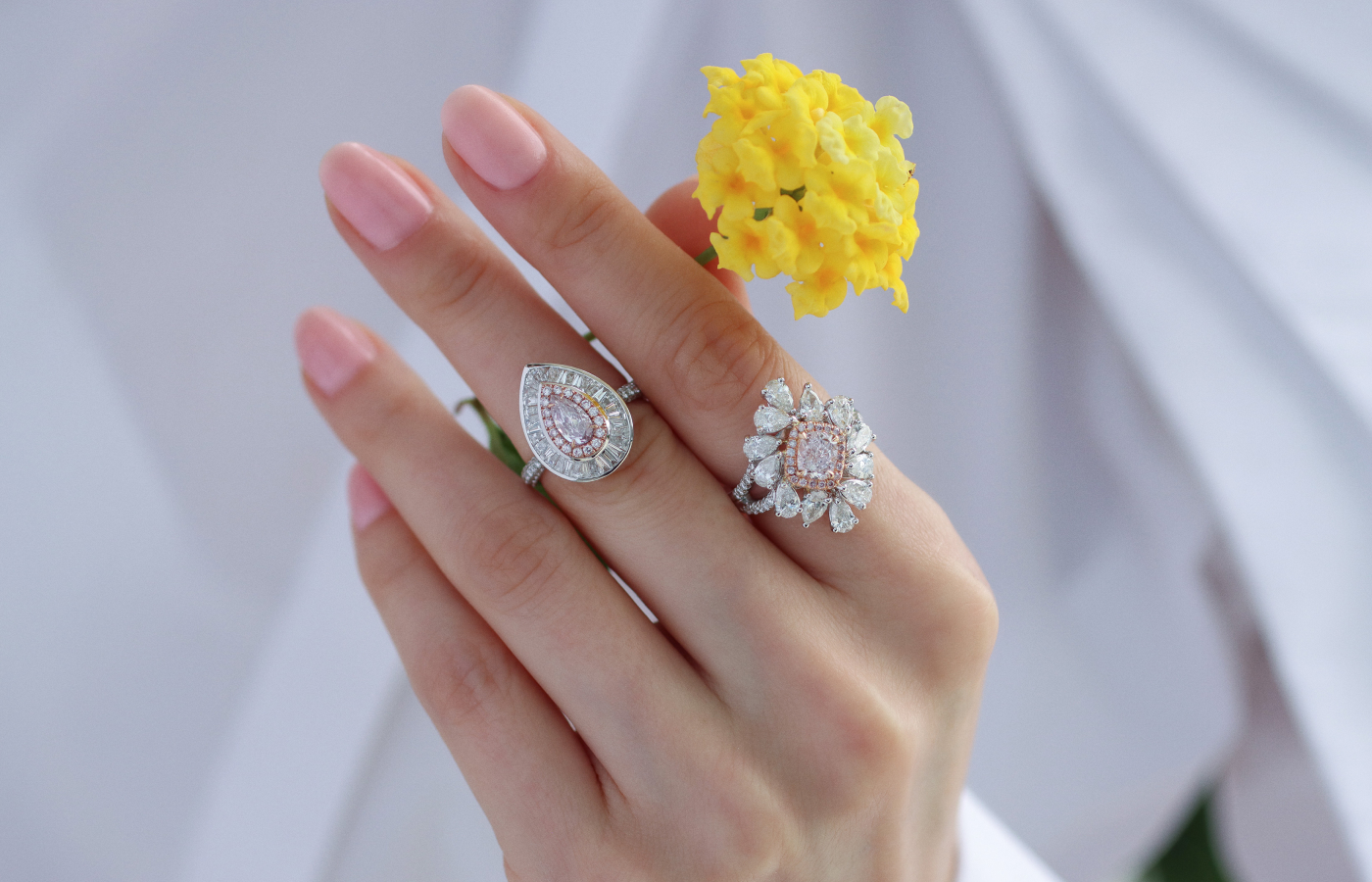 Katerina Perez wears a ring with a pear-shaped 0.35 carat fancy pink diamond (left) with tapered and round diamonds and a second ring with a 1.01 carat, SI2 clarity light pink diamond, surrounded by 12 pear-shaped diamonds of 1.93 carats and further pink and colourless diamonds, both in 18k white gold
