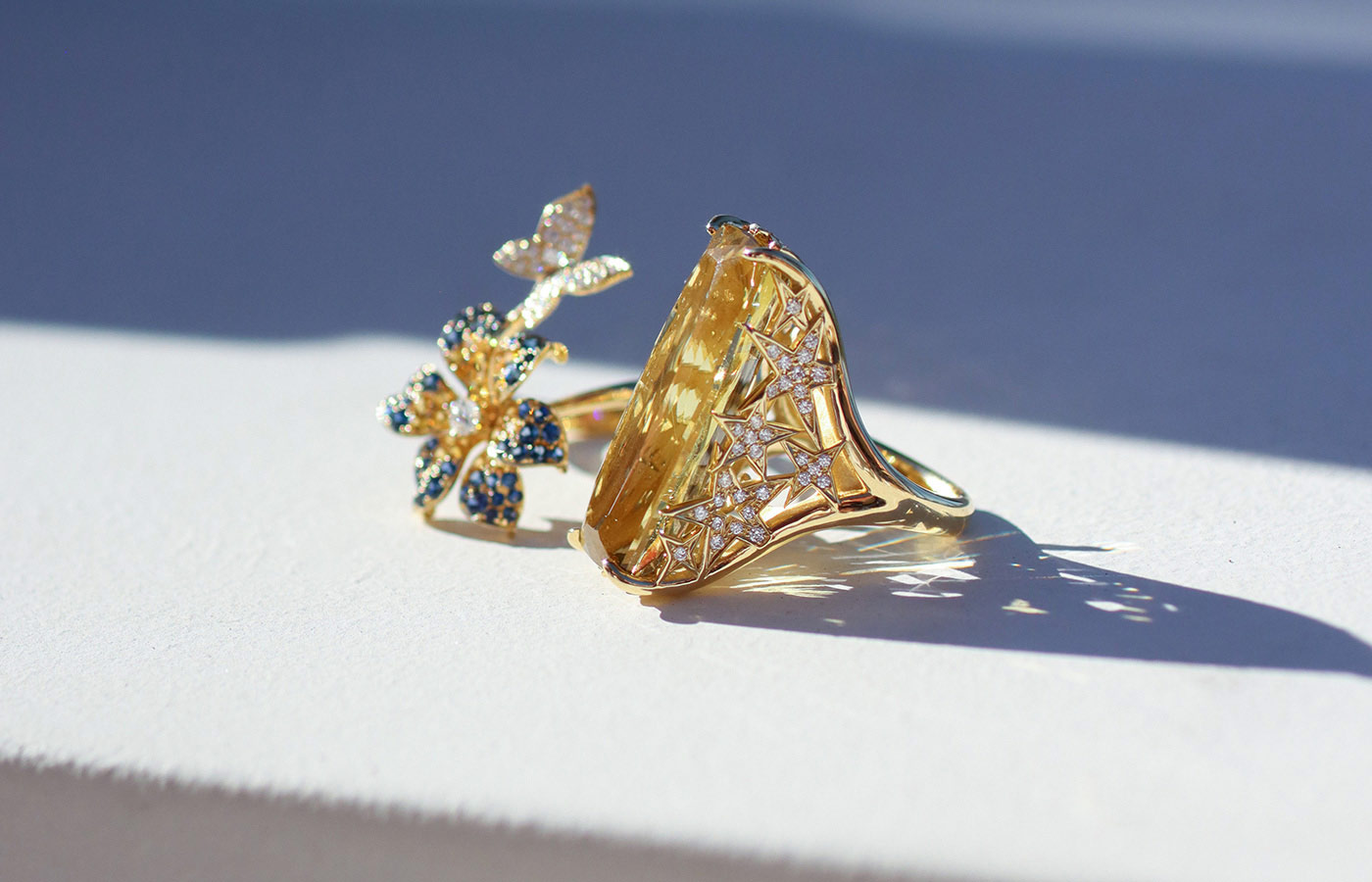  A closer look at two rings by Lisa Nik, including the Butterfly Flower Bypass ring from the Rainbow collection with 1.6 carats of yellow and blue sapphires and diamonds, alongside a 20.30 carat golden beryl and diamond ring from the Colors collection, both in 18k yellow gold