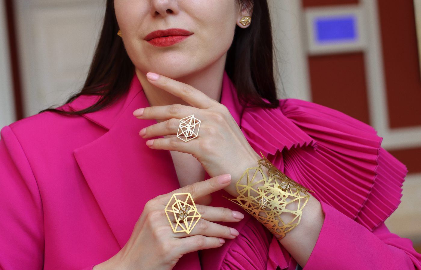Katerina Perez wears pieces from the Shattered collection by Robert Guild Jewelry, including a cuff bracelet, two rings and a pair of stud earrings set with reverse-set diamonds, all in 18k yellow gold 