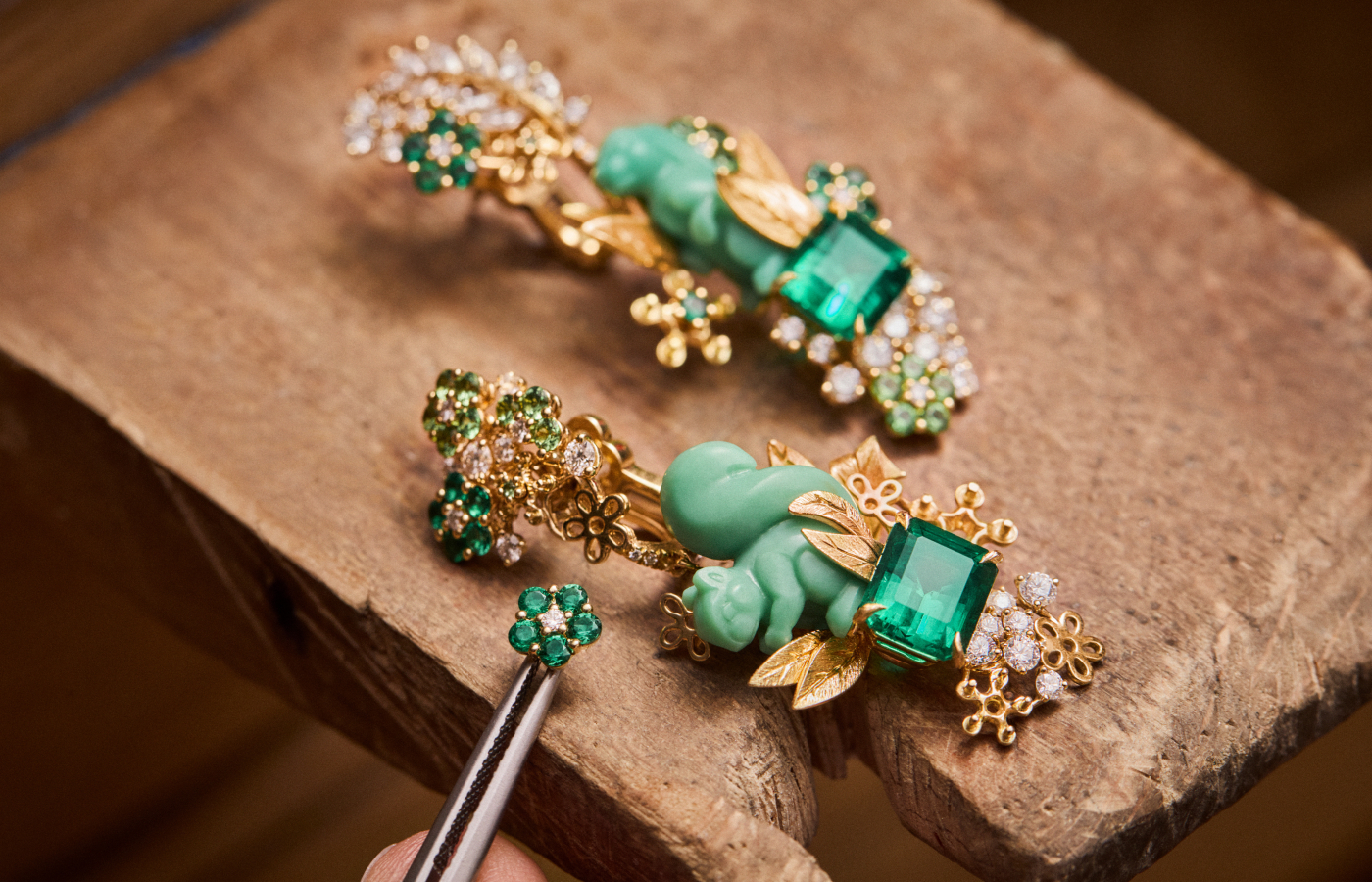  The making of the Diorama Forêt Enchantée asymmetric earrings, including emerald and diamond flowers and a glyptic chrysoprase squirrel and rabbit, surrounded by diamonds, emeralds, tsavorite garnets, and pearls, set in engraved 18k yellow gold