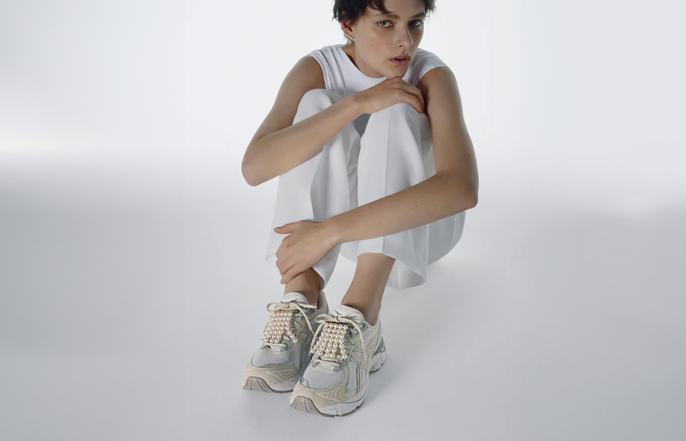 Model wears Tasaki x Asics trainers with Akoya pearls and 18k yellow gold, from the Balance Fringe collection