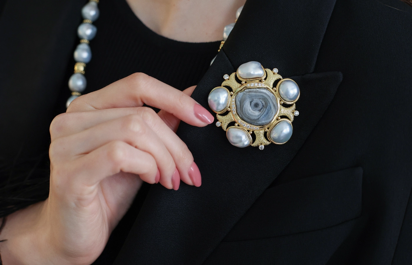  A closer look at a pin by Elizabeth Gage, set with a chalcedony rose, textured ‘fish tail’ motifs in 18k yellow gold, five South Sea baroque grey pearls and 22 round brilliant-cut diamonds 