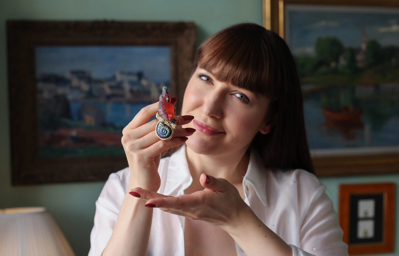  Katerina Perez holds the Mozart pin by Elizabeth Gage formed of a carved orange-red tourmaline parrot cameo with quartz eyes and blue tourmaline plume, totalling 102.13 carats, with a spectrolite snail cameo of 7.24 carats, all in 18k yellow gold 