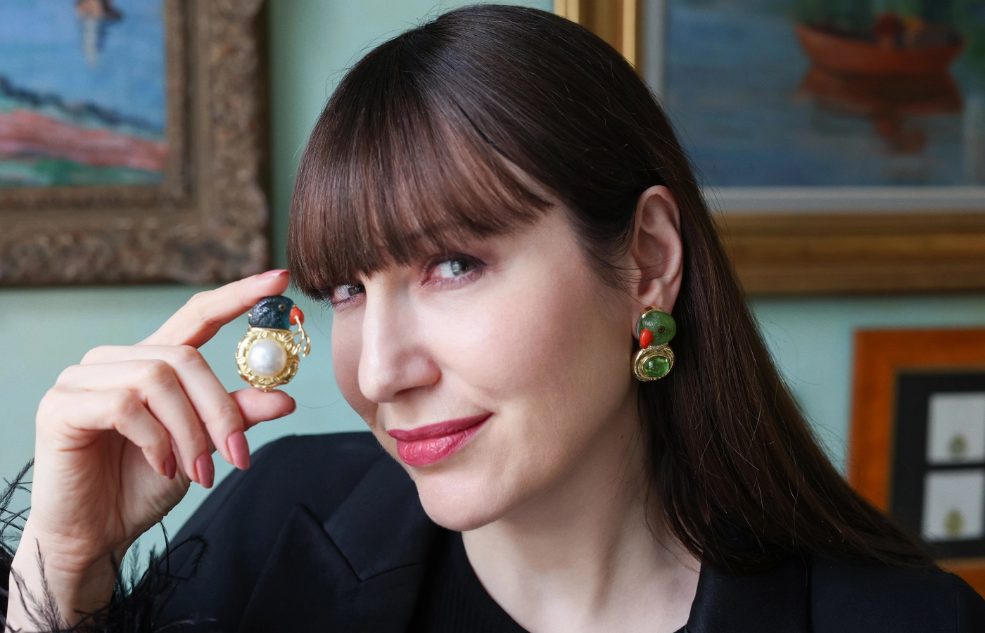  Katerina Perez wears parrot earrings by Elizabeth Gage with two carved peridot parrot cameos with coral beaks and painted rock crystal eyes, totalling 55.13 carats, plus 17.60 carats of peridot cabochons, alongside the 21.23 carat blue tourmaline and coral parrot head cameo pin with a South Sea pearl