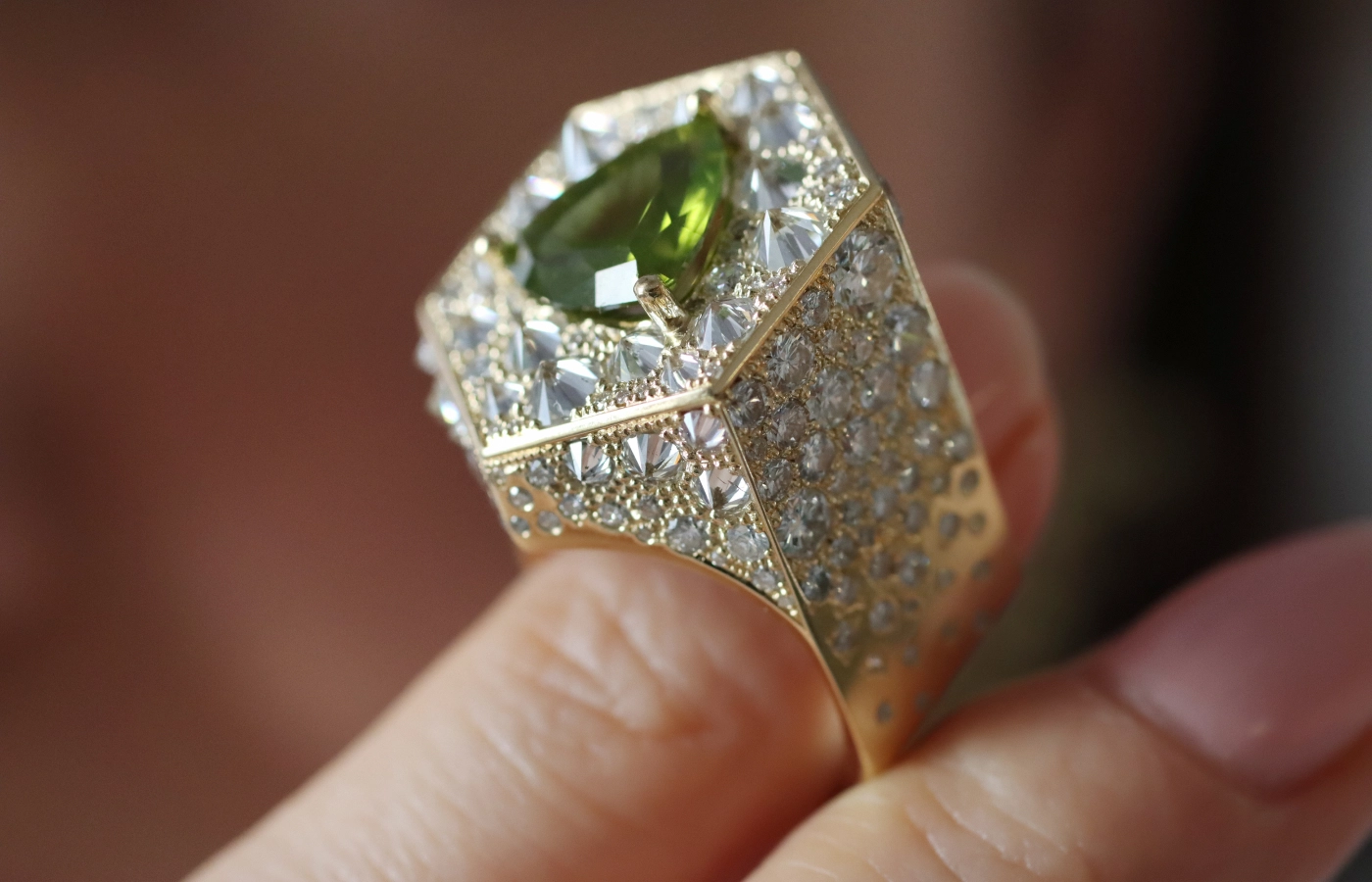  Hugo Cahill Perseya Lumen ring from the Renaissance High Jewellery collection with a 3.05 carat trillion-cut peridot from Pakistan alongside reverse-set diamonds in 18k palladium white gold and 18k gold 