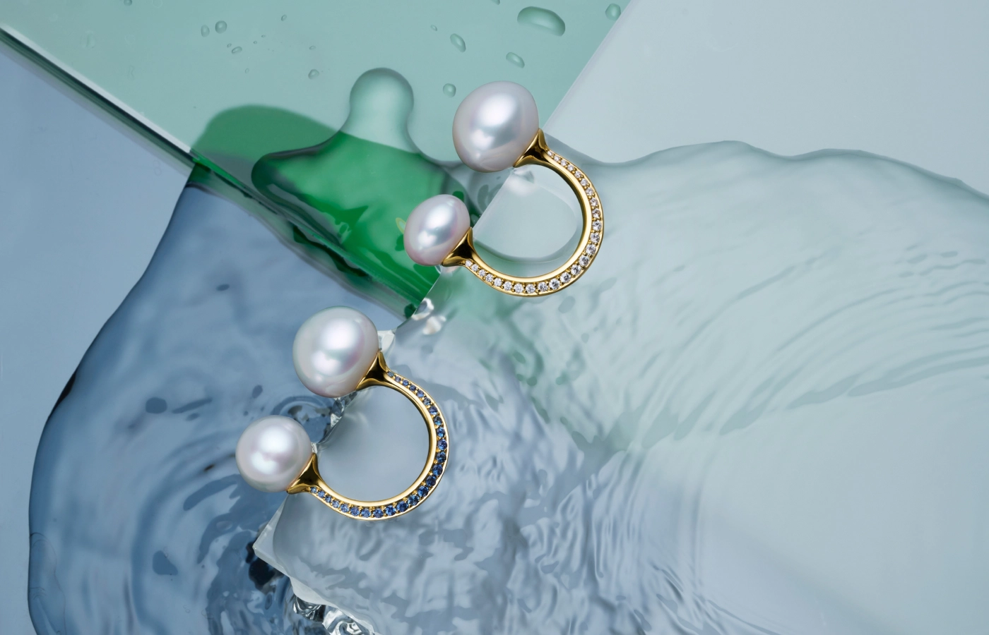 Paspaley Double Pearl Split rings from the Dive collection with button Australian South Sea pearls, blue sapphires (left), and white diamonds, set in 18k yellow gold 