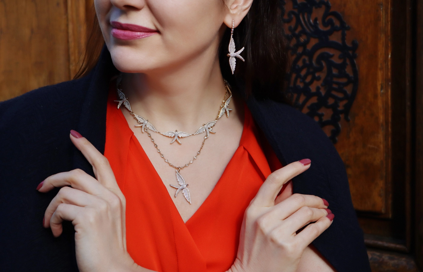 Katerina Perez wears jewellery from the Lionheart Wings of Love collection, including the Wings of Love Diamond Swallow charm, the Diamond Swallow necklace, and a pair of drop earrings with 2.15 carats of diamonds