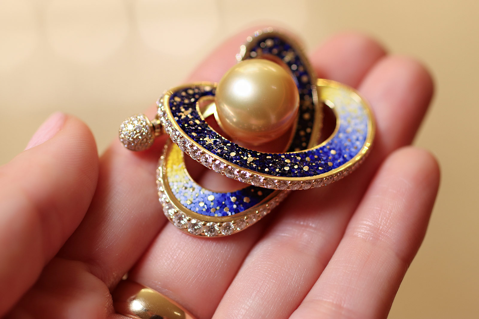  The Sicis Saturno brooch inspired by the rings of the planet Saturn, crafted in 18k yellow gold with a large South Sea pearl, micromosaics, and diamonds