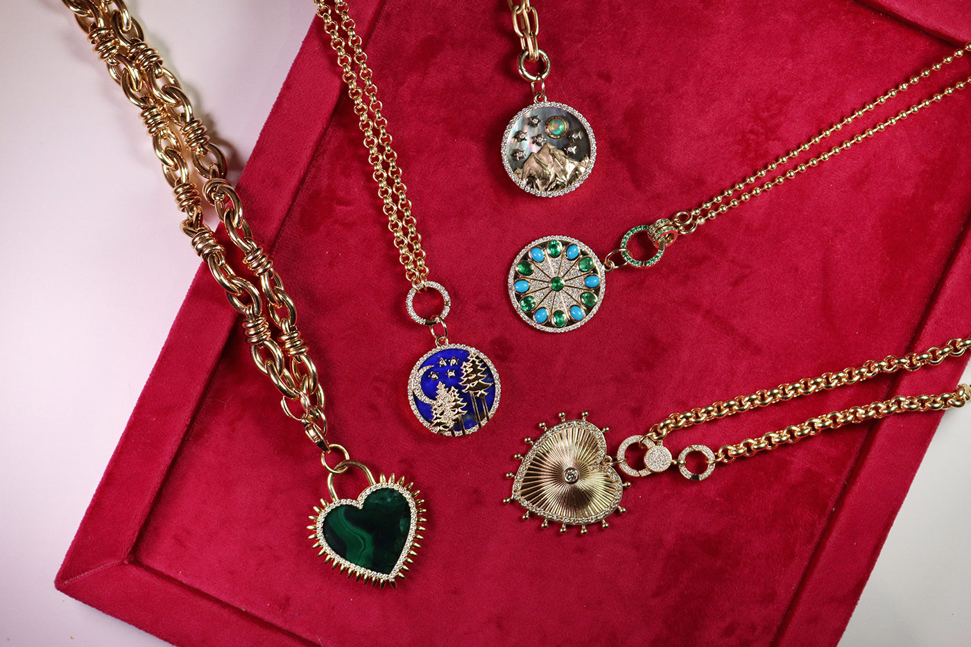 A selection of Medallions by Lionheart, including the colourful Serenity Amulet charm with 1.15 carats of diamonds, 0.95 carats of oval-shaped emeralds and 1.06 carats of turquoise cabochons, set in 14k yellow gold 